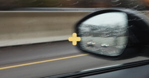 sideview mirror view of tailgating cars in rainy weather on a highway